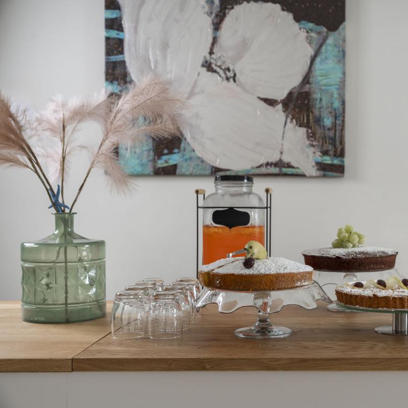 Tavola imbandita con dolci, pane e bevande, atmosfera accogliente e invitante.