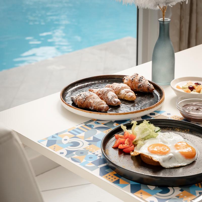 Colazione invitante con croissant e uova al sole, vista piscina rilassante.